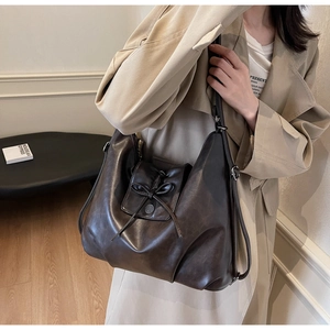 Detail of a large dark brown faux leather tote with vintage metal buckle and drawstring bow