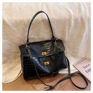 Detailed view of black crocodile pattern leather texture with gold metal buckles on bag