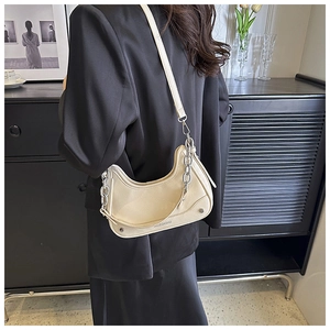 Détail du sac lune crème avec des accents de chaîne argentée et texture de cuir fini