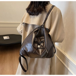 Detail of the dark brown leather tote with a bow accent and silver metal snap button
