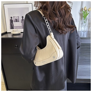 Détail du sac selle crème avec bandoulière chaîne argentée porté par un mannequin