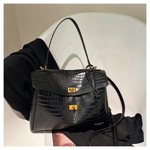 Detail of black crocodile texture tote bag with gold hardware on a stylish white chair