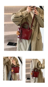 Borsa a secchiello in pelle lucida rosso scuro con goffratura e ciondolo a orsetto