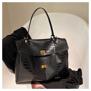 Detail of black crocodile texture tote bag with gold twist lock and elegant top handle