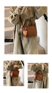 Dettaglio di una borsa a secchiello in pelle PU marrone con orsetto e sciarpa a quadri