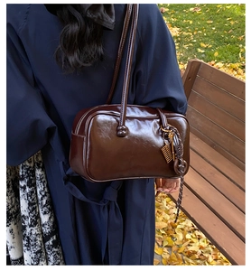 Détail du sac Boston vintage en cuir ciré marron avec breloques et bandoulière