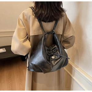 Detail view of large black PU leather tote bag with drawstring bow and magnetic metal buckle