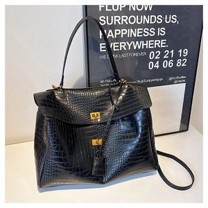 Close-up of black crocodile pattern leather tote with gold twist-lock clasps