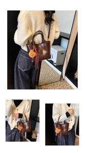 Dettaglio borsa tote in pelle marrone con logo a sbalzo e grazioso ciondolo a forma di orsetto