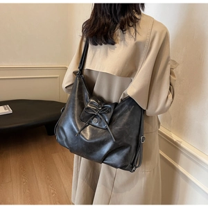 Detail view of black hobo bag in soft oil wax leather with bow and metal buckle accents