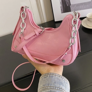 Sac croissant rose avec chaîne argentée et rivets présenté à la main de façon élégante