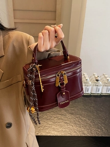 Retro burgundy box handbag with gold hardware and charm decorations in hand display