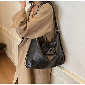 Detail view of black soft leather tote bag with bow drawstring and metal snap button closure