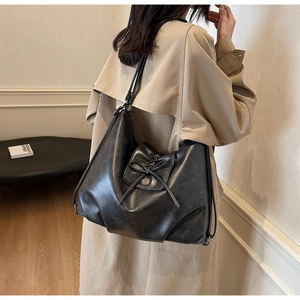 Detail of black tote bag with bow ribbon and silver metal buckle on smooth leather