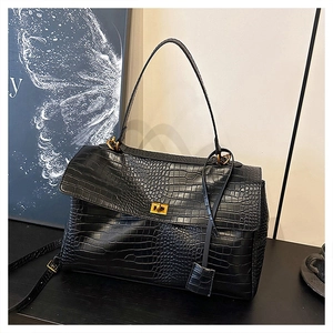 Close-up of black crocodile pattern leather tote bag with gold metal clasp and handle