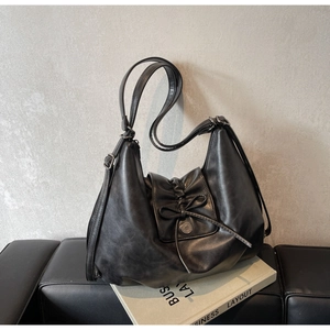 Detail of a vintage black hobo bag with a bow tie, metal buckle, and leather texture