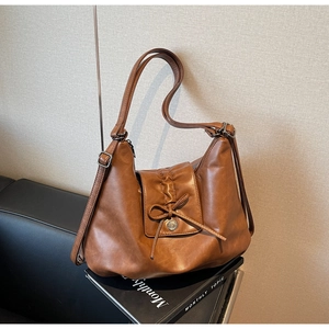 Detail view of brown retro leather shoulder bag with drawstring bow and metal buckle