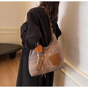 Vista dettagliata di una borsa tote vintage marrone con ciondolo a forma di orsetto