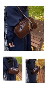 Détail du sac polochon en cuir ciré marron foncé avec pompon tressé sur un banc