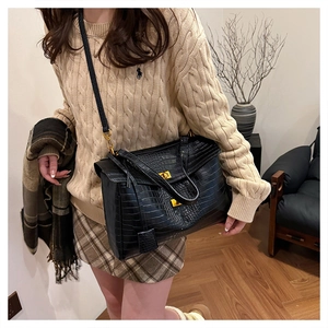 Detailed macro view of black crocodile pattern leather tote with gold metal lock closure
