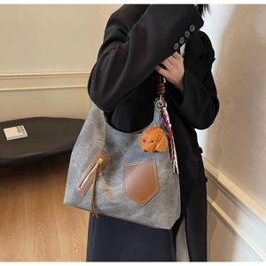Dettaglio della borsa tote in tela grigia con tasche in pelle marrone e ciondolo