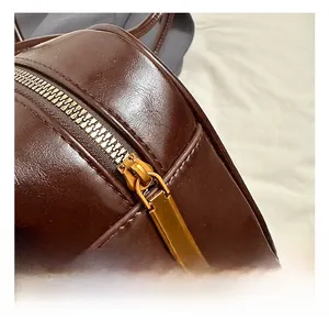 Détail macro d'une fermeture éclair dorée sur un sac à main en cuir marron foncé