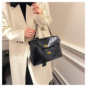 Detailed close-up showing glossy crocodile pattern texture and gold buckles of black tote bag