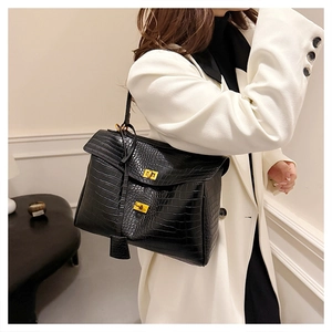 Detail of black crocodile pattern leather tote bag with gold twist locks worn with a blazer