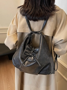 Minimalist black PU leather backpack with drawstring bow and metal logo on a model