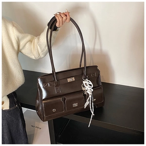 Detailed view of dark brown polished leather tote with silver metal twist locks and charm