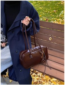 Détail du sac Boston marron foncé en cuir ciré avec finition brillante sur un banc
