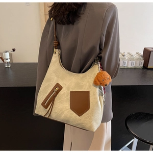 Dettaglio della borsa tote in tela con finiture in pelle marrone, frange e ciondolo a cane