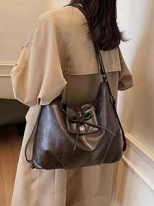 Retro brown oversized hobo tote bag with bow detail and vintage metal button on model