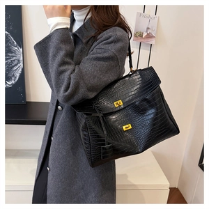Close-up of black crocodile pattern leather tote bag with elegant gold twist locks