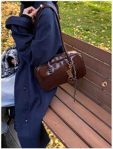 Détail d'un sac Boston en cuir ciré marron foncé avec charm boulier vintage brillant