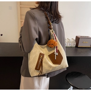 Dettaglio della borsa tote in tela con finiture in pelle marrone e orsetto