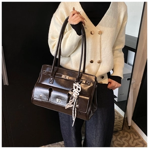 Detail of dark brown glossy tote bag with front pockets and Baby letter charm