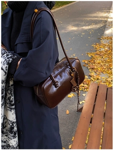 Détail du sac Boston en cuir brillant marron foncé avec pendentif en métal de style rétro