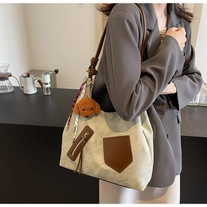 Dettaglio della borsa tote in tela vintage con tasca in pelle e ciondolo a forma di cane