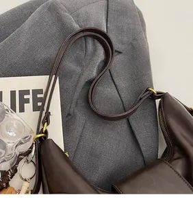 Detailed close-up of dark brown leather bag with adjustable strap and gold metal hooks