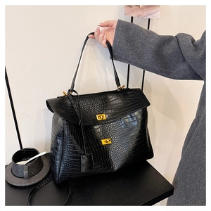 Detail of black crocodile pattern leather tote with gold buckles and fixed handle