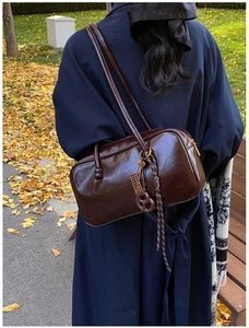 Détail du sac Boston en cuir ciré marron foncé avec porte-clés boulier décoratif au côté