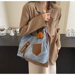 Dettaglio della borsa tote vintage grigio-blu con tasche in pelle marrone e ciondolo