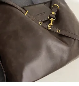 Detail view of dark brown faux leather tote with gold-tone metal hardware and adjustable strap