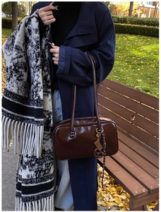 Détail du sac Boston en cuir ciré vintage avec charme en métal dans un décor d'automne