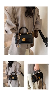 Close-up of black glossy leather bag with golden square buckle and woven rope detail