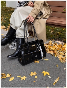 Close-up of black glossy leather briefcase bag with silver lock and silk scarf detail