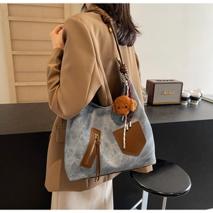 Borsa tote in denim blu con accenti in pelle marrone e ciondolo a forma di cane in peluche