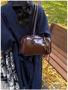 Détail du sac Boston vintage en cuir ciré marron avec pendentif boulier doré chic