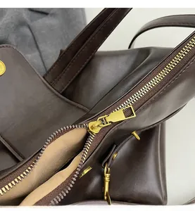 Detail view of premium dark brown leather texture and smooth golden metallic zipper closure